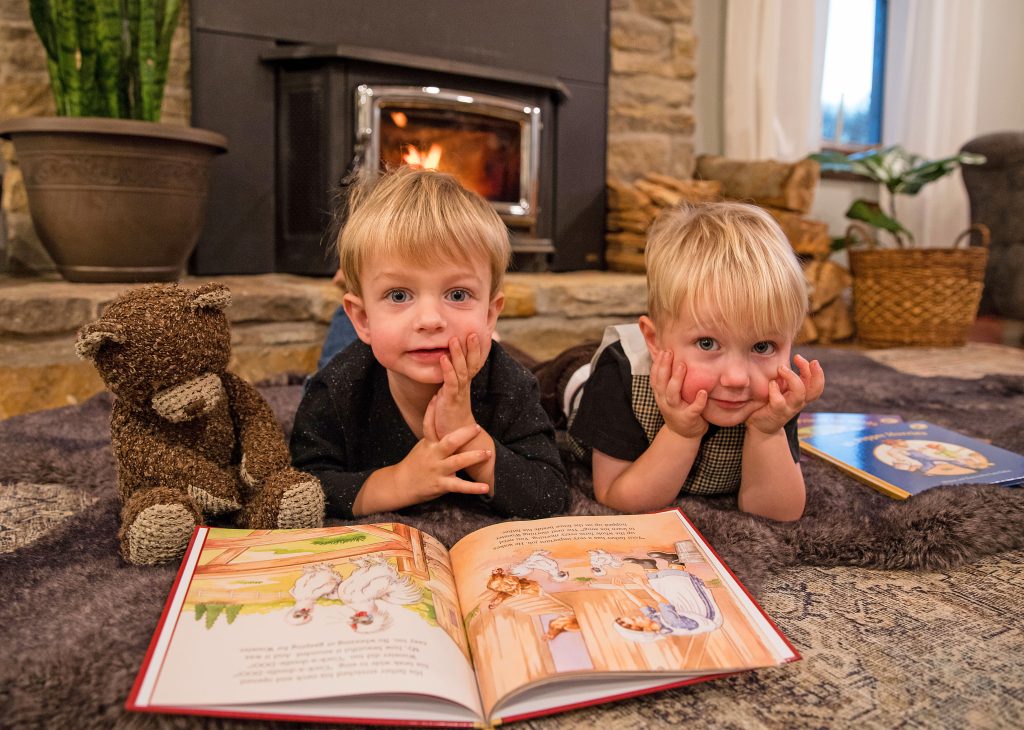 Two little boys looking up over book