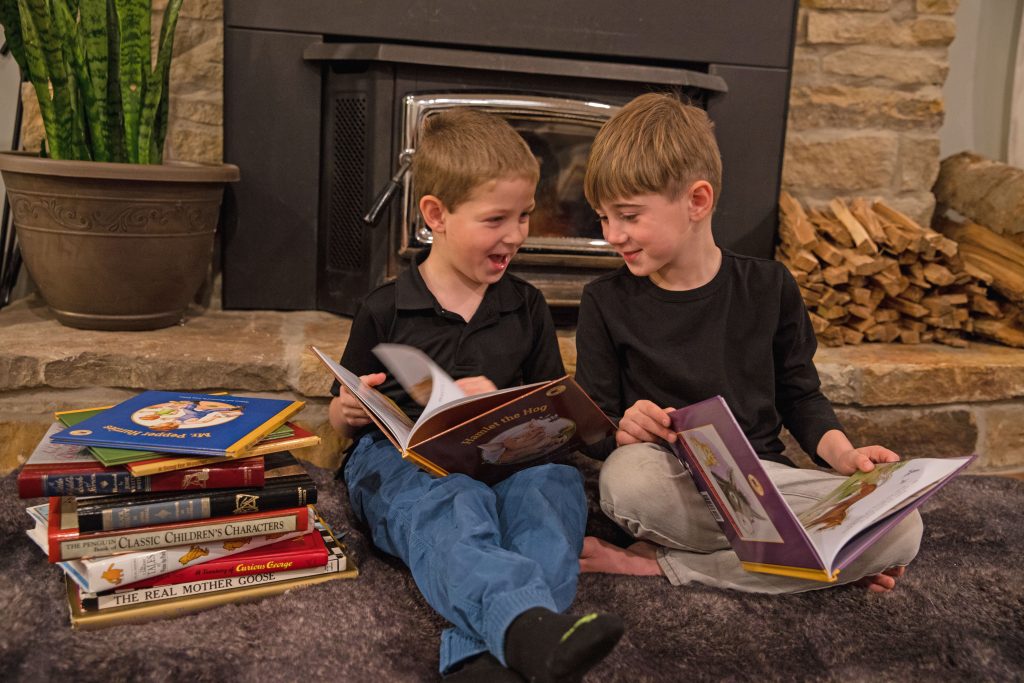 Two boys in front of fire, reading