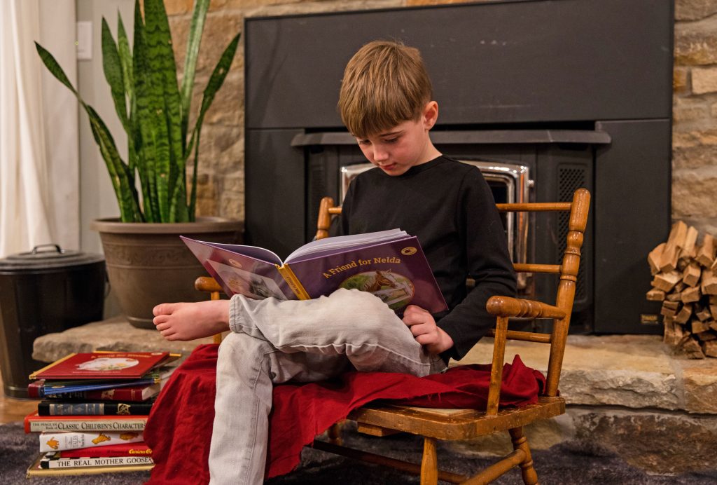 Boy sits on old chair reading book