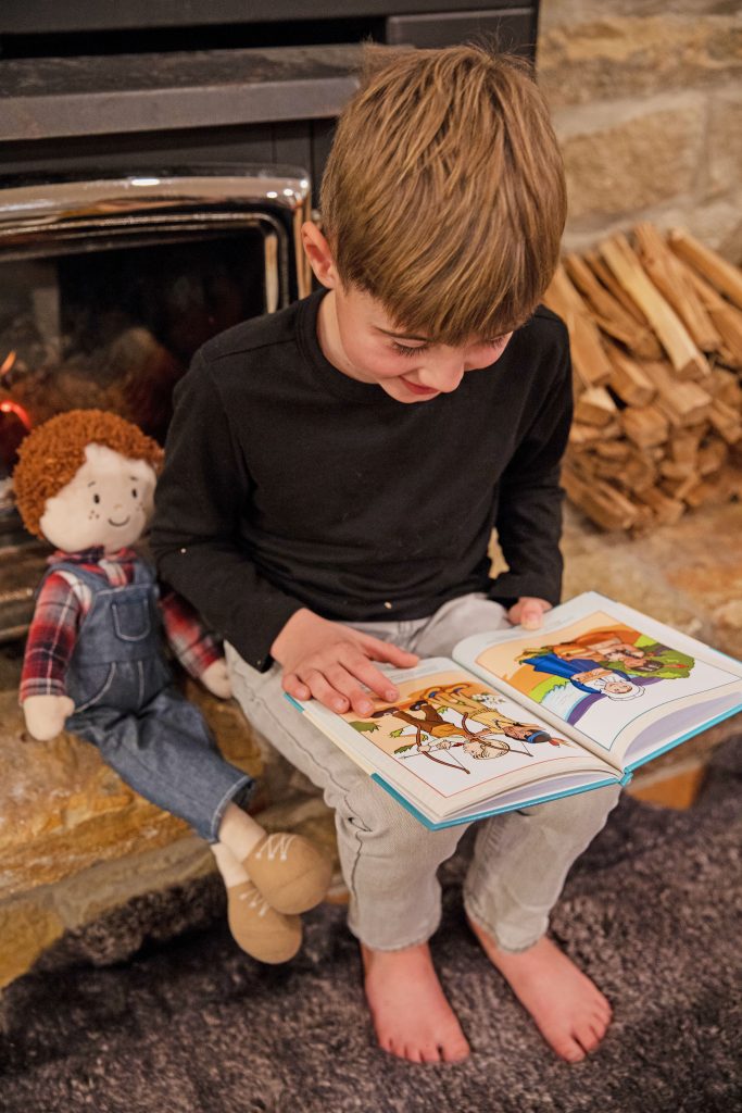 little boy reading with doll