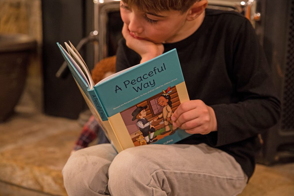 little boy reading with chin propped on hand.