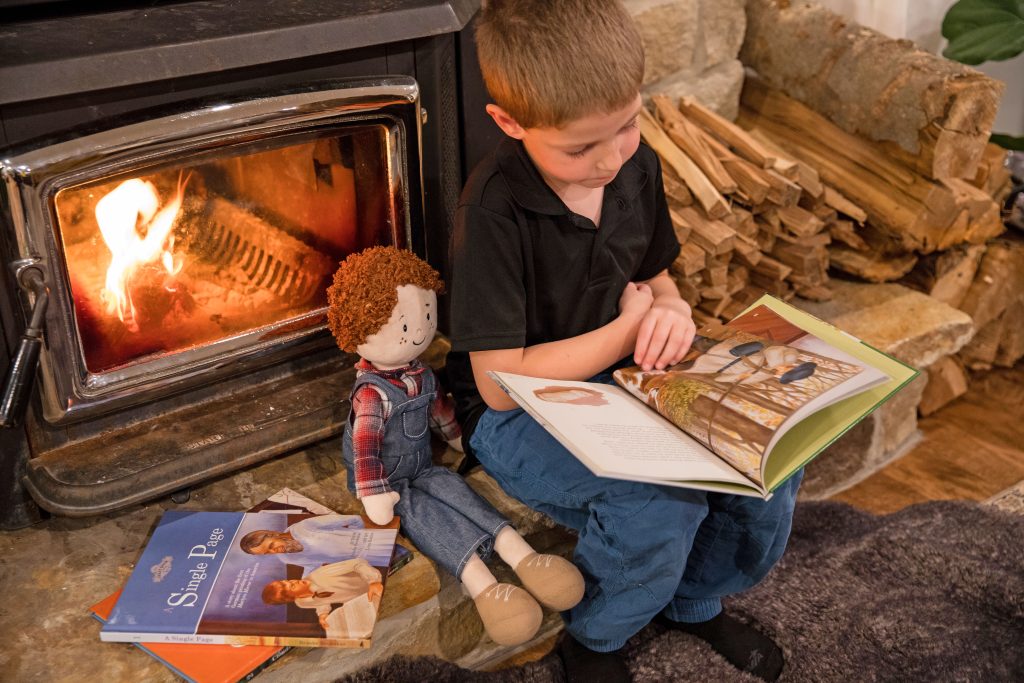 Little boy and a doll sit and read a book